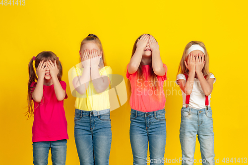 Image of Happy children playing and having fun together on yellow studio background