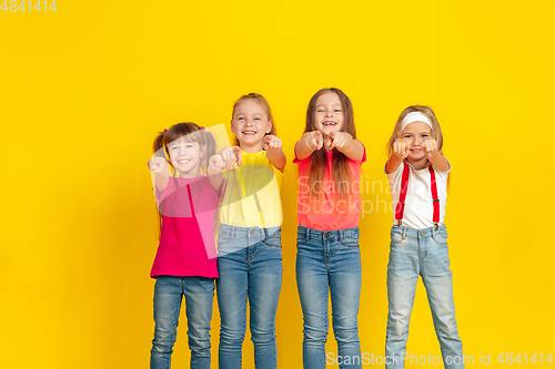 Image of Happy children playing and having fun together on yellow studio background