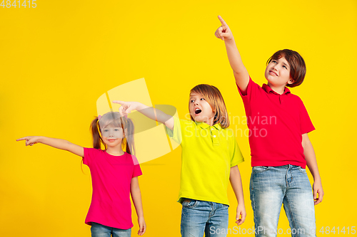 Image of Happy children playing and having fun together on yellow studio background