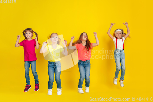 Image of Happy children playing and having fun together on yellow studio background