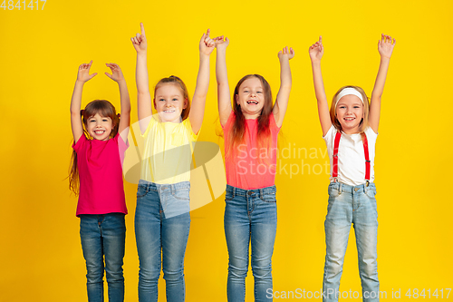 Image of Happy children playing and having fun together on yellow studio background
