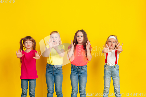 Image of Happy children playing and having fun together on yellow studio background