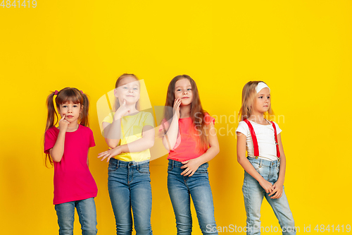 Image of Happy children playing and having fun together on yellow studio background