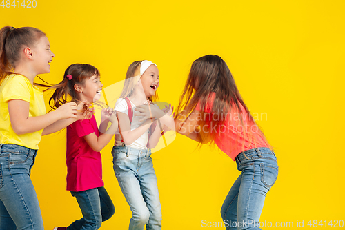 Image of Happy children playing and having fun together on yellow studio background
