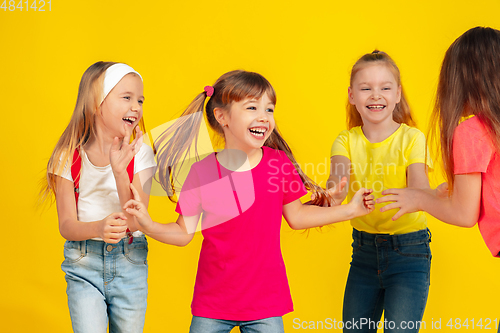 Image of Happy children playing and having fun together on yellow studio background