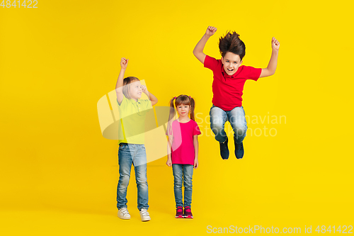 Image of Happy children playing and having fun together on yellow studio background