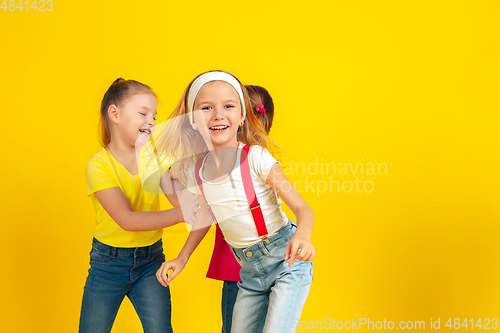 Image of Happy children playing and having fun together on yellow studio background