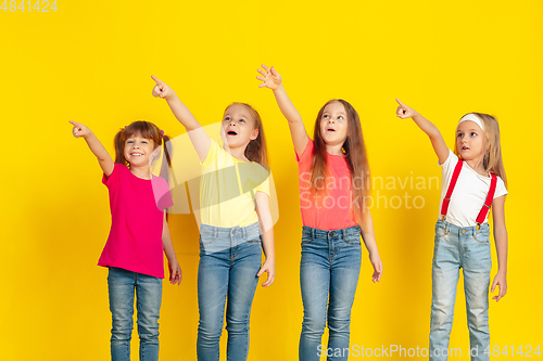 Image of Happy children playing and having fun together on yellow studio background