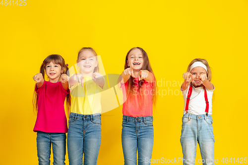 Image of Happy children playing and having fun together on yellow studio background
