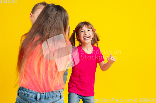 Image of Happy children playing and having fun together on yellow studio background