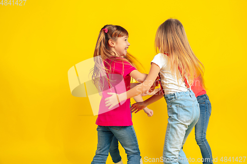 Image of Happy children playing and having fun together on yellow studio background