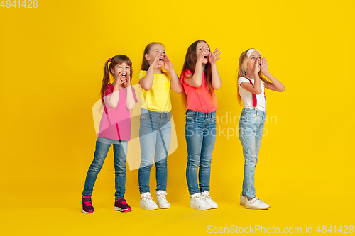 Image of Happy children playing and having fun together on yellow studio background