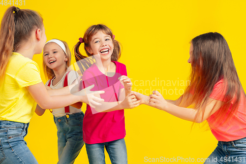 Image of Happy children playing and having fun together on yellow studio background