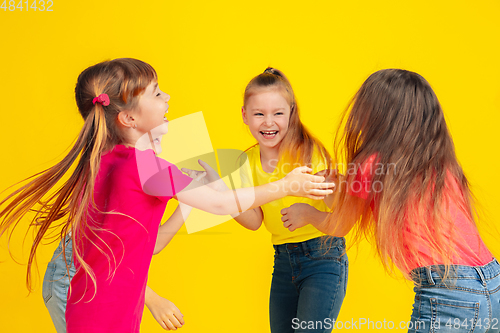 Image of Happy children playing and having fun together on yellow studio background