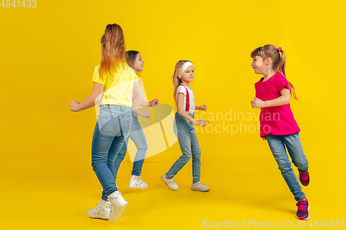 Image of Happy children playing and having fun together on yellow studio background