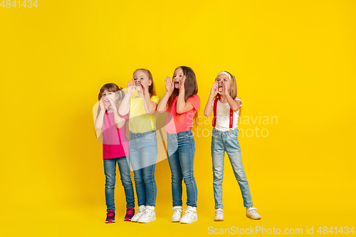 Image of Happy children playing and having fun together on yellow studio background