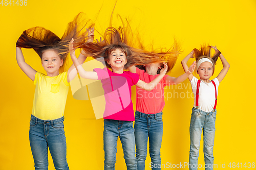 Image of Happy children playing and having fun together on yellow studio background