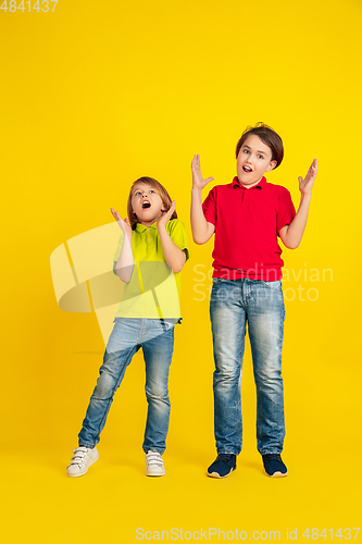 Image of Happy children playing and having fun together on yellow studio background