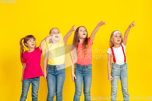 Image of Happy children playing and having fun together on yellow studio background