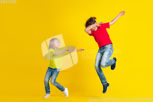 Image of Happy children playing and having fun together on yellow studio background