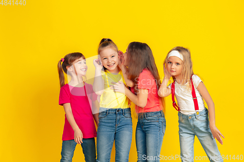 Image of Happy children playing and having fun together on yellow studio background