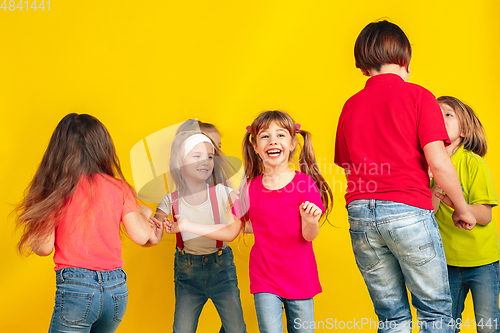 Image of Happy children playing and having fun together on yellow studio background