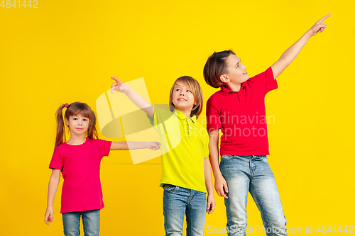Image of Happy children playing and having fun together on yellow studio background