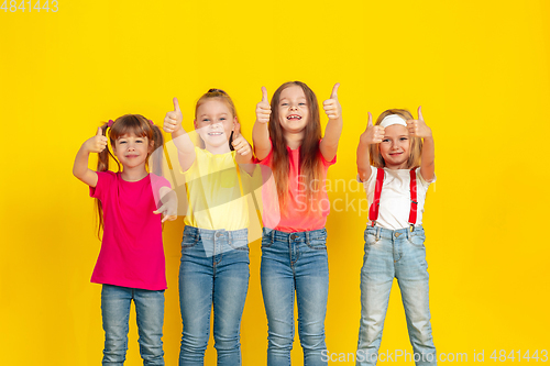 Image of Happy children playing and having fun together on yellow studio background