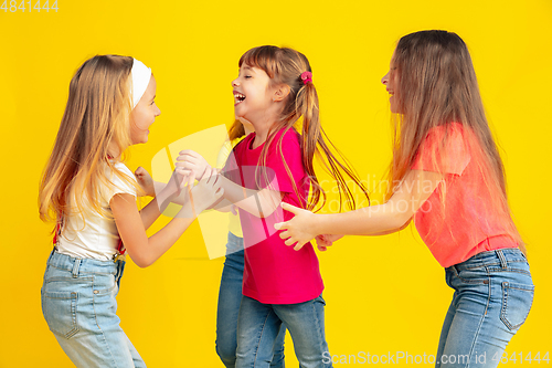 Image of Happy children playing and having fun together on yellow studio background