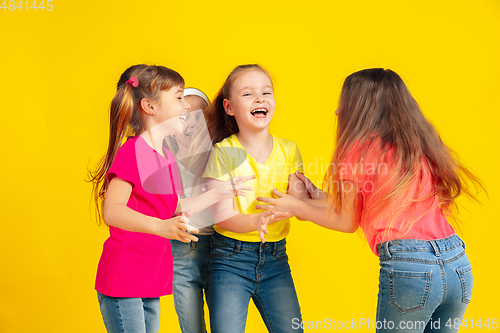 Image of Happy children playing and having fun together on yellow studio background