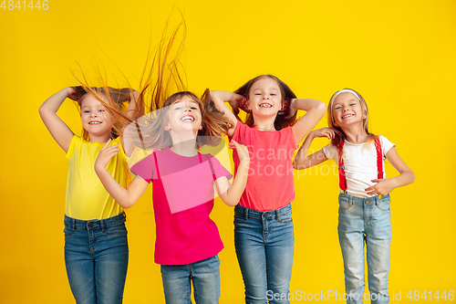 Image of Happy children playing and having fun together on yellow studio background