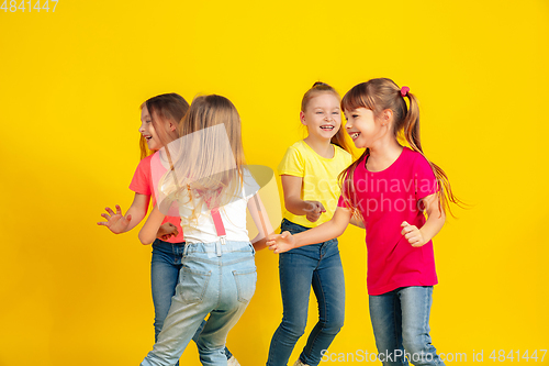 Image of Happy children playing and having fun together on yellow studio background