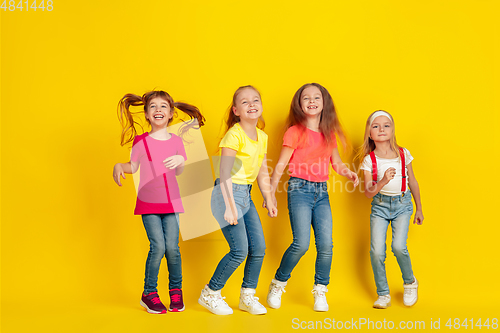 Image of Happy children playing and having fun together on yellow studio background