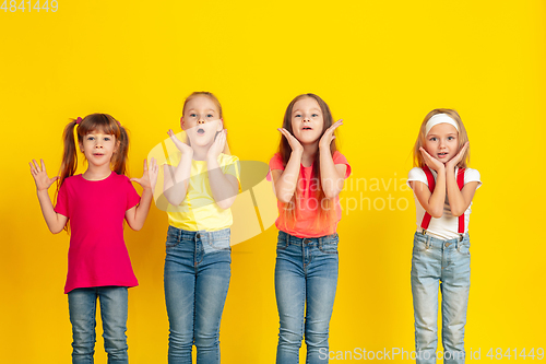 Image of Happy children playing and having fun together on yellow studio background