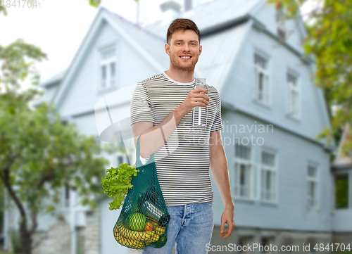 Image of man with food in bag and water in glass bottle