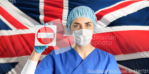 Image of british doctor or nurse in mask showing stop sign