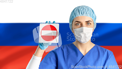 Image of russian doctor or nurse in mask showing stop sign