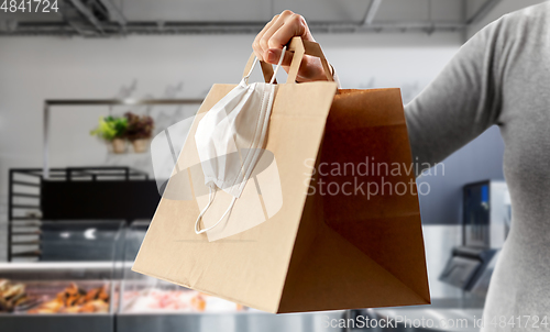 Image of woman with food in bag and mask at grocery store