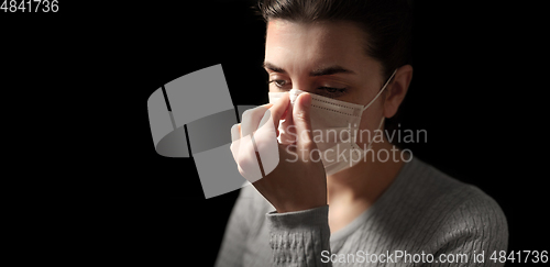 Image of sick woman adjusting protective medical face mask