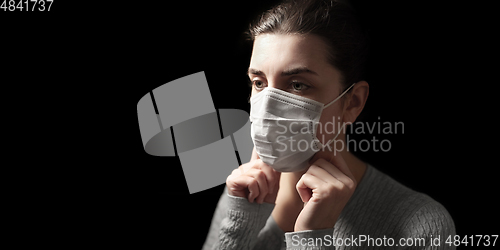 Image of sick woman adjusting protective medical face mask