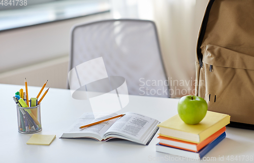 Image of books, apple and school supplies on table at home