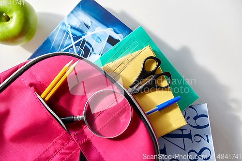 Image of backpack with books, school supplies and apple