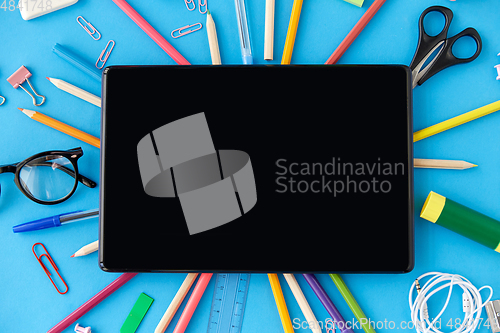 Image of tablet pc and school supplies on blue background