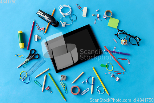 Image of tablet pc and school supplies on blue background