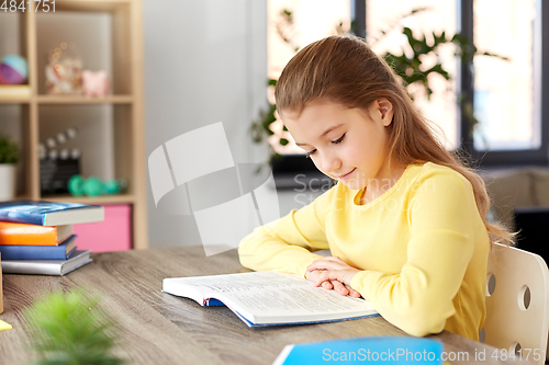 Image of little student girl reading book at home