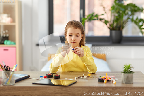 Image of happy girl playing with robotics kit at home