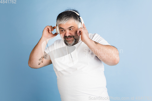 Image of Handsome caucasian plus size male model isolated on blue studio background. Concept of inclusion, human emotions, facial expression