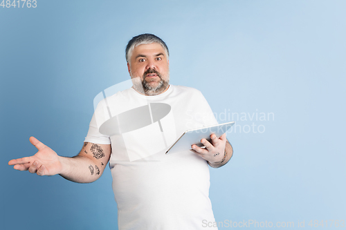 Image of Handsome caucasian plus size male model isolated on blue studio background. Concept of inclusion, human emotions, facial expression