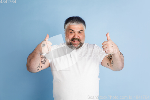 Image of Handsome caucasian plus size male model isolated on blue studio background. Concept of inclusion, human emotions, facial expression