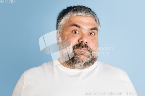 Image of Handsome caucasian plus size male model isolated on blue studio background. Concept of inclusion, human emotions, facial expression